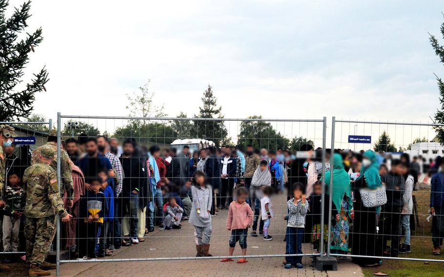 Afghan evacuees wait by fencing on Rhine Ordnance Barracks in Kaiserslautern, Germany, for the evening meal, Aug. 30, 2021. The Army installation was transformed in four days to help nearby Ramstein Air Base temporarily house thousands of Afghans who have been airlifted out of Kabul since the Taliban seized control in Afghanistan.