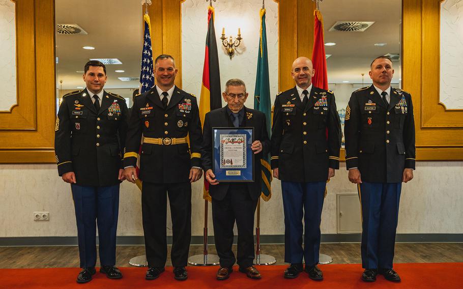 Kenneth Aungst, center, a retired Army first sergeant and Vietnam veteran, receives the 7th Army Training Command’s Good Neighbor Award. Also participating in the ceremony in Grafenwoehr, Germany, on April 19, 2024, were, left to right: Sgt. Maj. Paul Fedorisin, the training command’s enlisted leader; commander Brig. Gen. Steven Carpenter; Col. Ryan Kendall, commander of the 12th Combat Aviation Brigade; and brigade Command Sgt. Maj. Kyle Clutter.