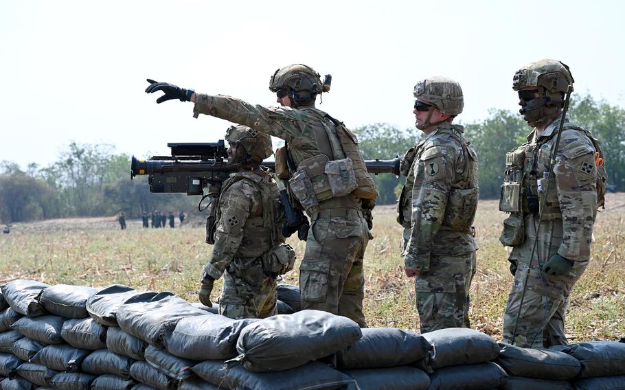 One soldier points to a target as three others stand by. 