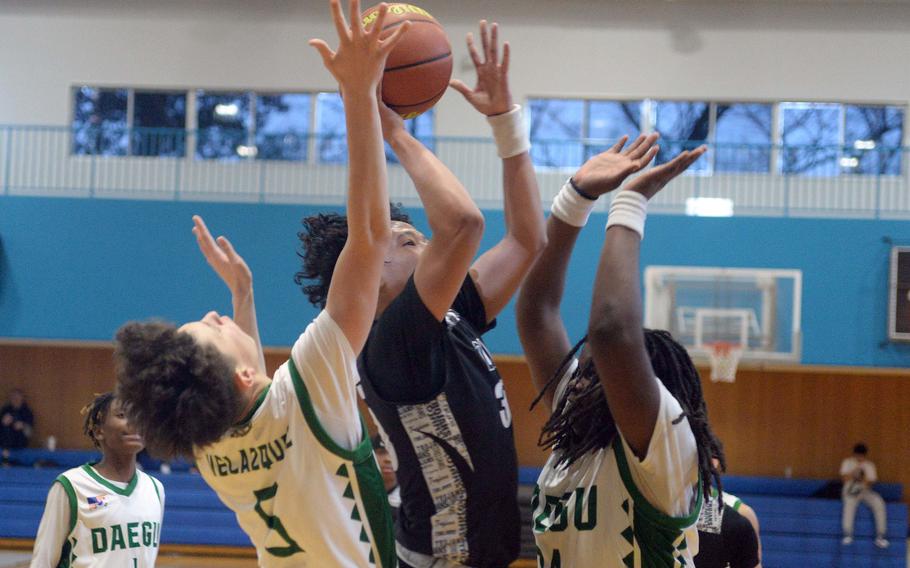 Zama's Kosey Hameen puts up a shot between Daegu defenders Jude Velazquez and Mauriece Sowu. The Trojans won 65-61.