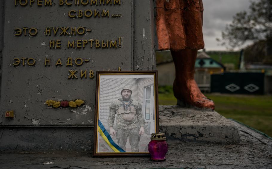 A picture of Ruslan Siksoi, killed near Izyum on April 13, 2022, stands on the World War II monument in Berezivka, Ukraine. Visits to memorials were discouraged because of the danger of attacks.