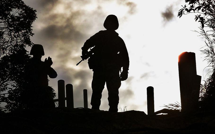 U.S. Marine Corps Sgt. Mike Anglen, center, stands atop a cliff as Sgt. Bryan Wallace of Pikin, Ill., waits for his turn before their rappelling exercise at Jungle Warfare Training Center in Camp Gonsalves, northern Okinawa, Japan, on Feb. 8, 2002. Okinawa on Sunday, May 15, 2022, marks the 50th anniversary of its return to Japan on May 15, 1972, which ended 27 years of U.S. rule after one of the bloodiest battles of World War II was fought on the southern Japanese island.
