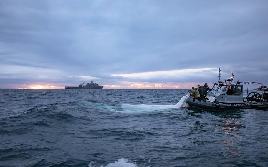 Sailors assigned to Explosive Ordnance Disposal Group 2 recover a high-altitude surveillance balloon off the coast of Myrtle Beach, South Carolina, while the Harpers Ferry-class dock landing ship USS Carter Hall (LSD 50) transits nearby, Feb. 5, 2023. 