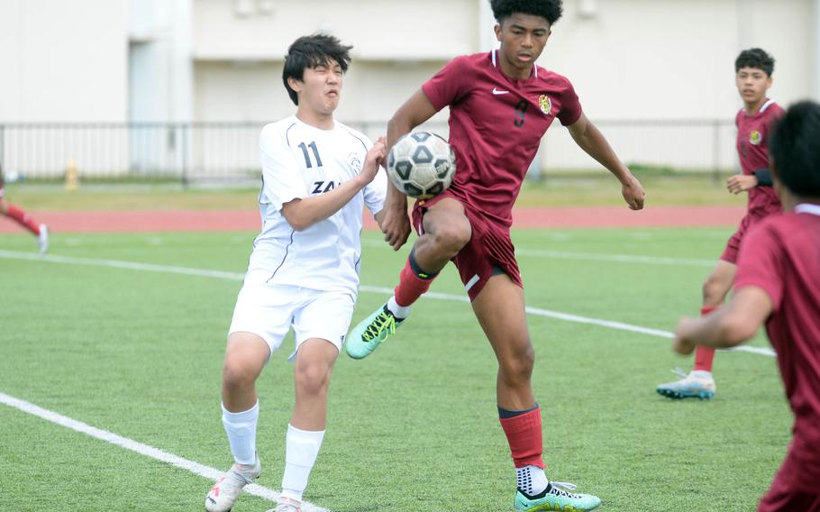 Zama’s Justin Knutson and Matthew C. Perry’s Jalen Cooley battle for the ball during Saturday’s DODEA-Japan boys soccer match. The Trojans and Samurai played to a 1-1 draw.