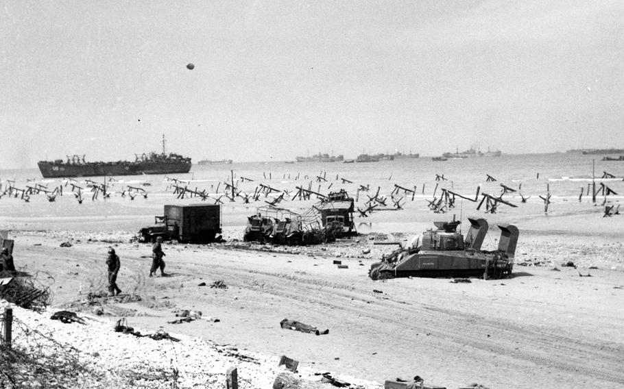 Scene on Omaha Beach on the afternoon of D-Day, 6 June 1944, showing casualties on the beach, a bogged-down Sherman tank, several wrecked trucks and German anti-landing obstructions. A LST is beached in the left distance and invasion shipping is off shore.  Official U.S. Navy Photograph, now in the collections of the National Archives.