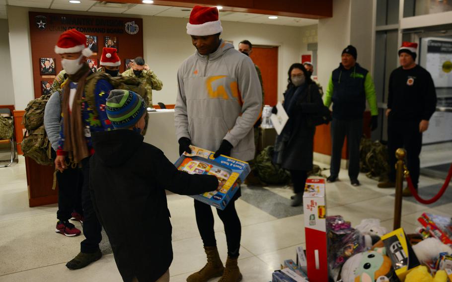 A child donates a toy at 2nd Infantry Division headquarters, Camp Humphreys, South Korea, Thursday, Dec. 2, 2021. The presents will be donated to South Korean orphans for Christmas.