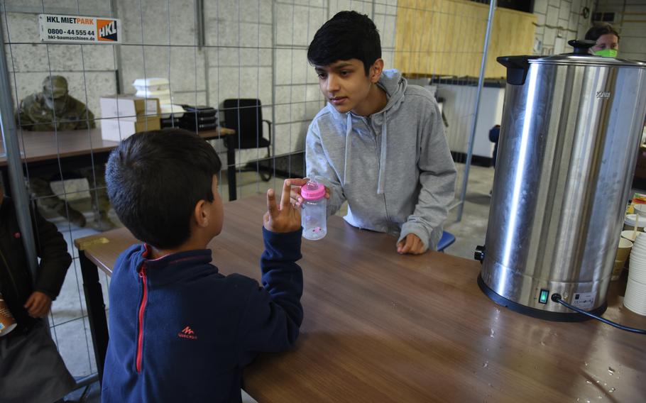 Erfan Ahmadi, 14, takes requests for formula and tea while volunteering at Rhine Ordnance Barracks, Germany, on Sept. 20, 2021. Ahmadi and his family are evacuees from Afghanistan. He speaks Dari, Pashto and English and is one of several Afghan teens who translate for American volunteers at the stations where baby formula and hot tea are served.