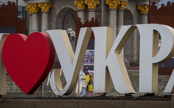 A woman and child walk behind a "I Love Ukraine" sign in Kyiv on March 14, 2024.