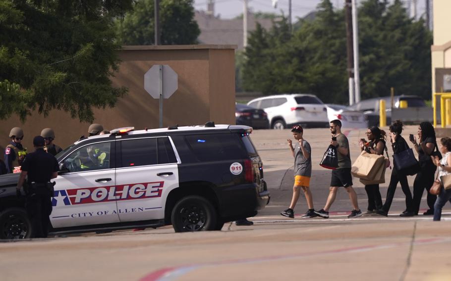 People raise their hands as they leave a shopping center following reports of a shooting, Saturday, May 6, 2023, in Allen, Texas. 