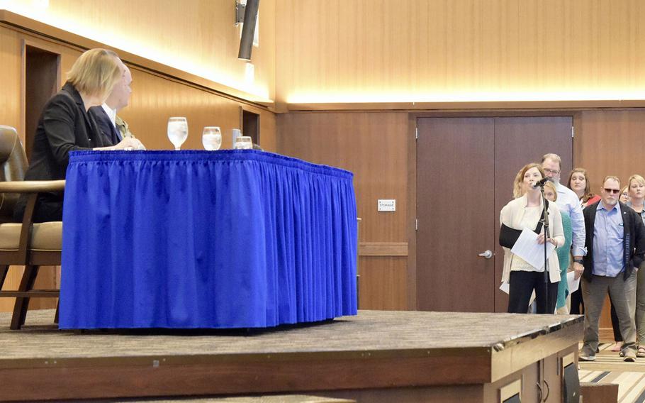 Kelly Pretorius speaks at a microphone about civilian health care during a town hall meeting at Kadena Air Base, Okinawa, Feb. 1, 2023.