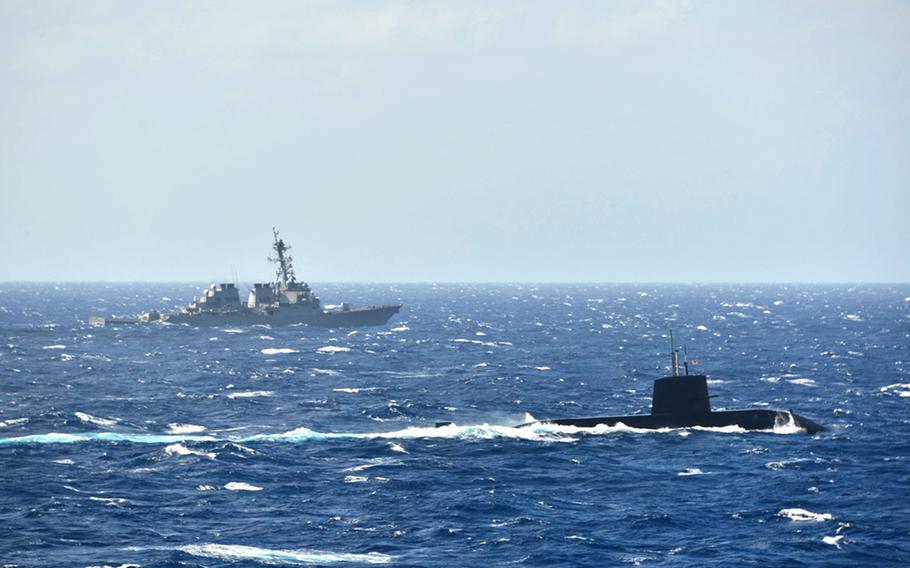 The guided-missile destroyer USS Milius sails alongside an unidentified Japan Maritime Self-Defense Force submarine during an anti-submarine warfare exercise in the South China Sea, Tuesday, Nov. 16, 2021.