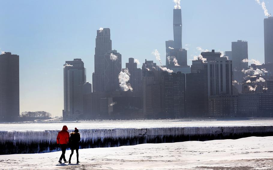 A couple walks along North Avenue Beach on the shore of Lake Michigan as temperatures hang in the single digits on January 26, 2022, in Chicago, Illinois. The coldest temperatures in more than a year have gripped the city but a slight warmup is expected to begin tomorrow. 