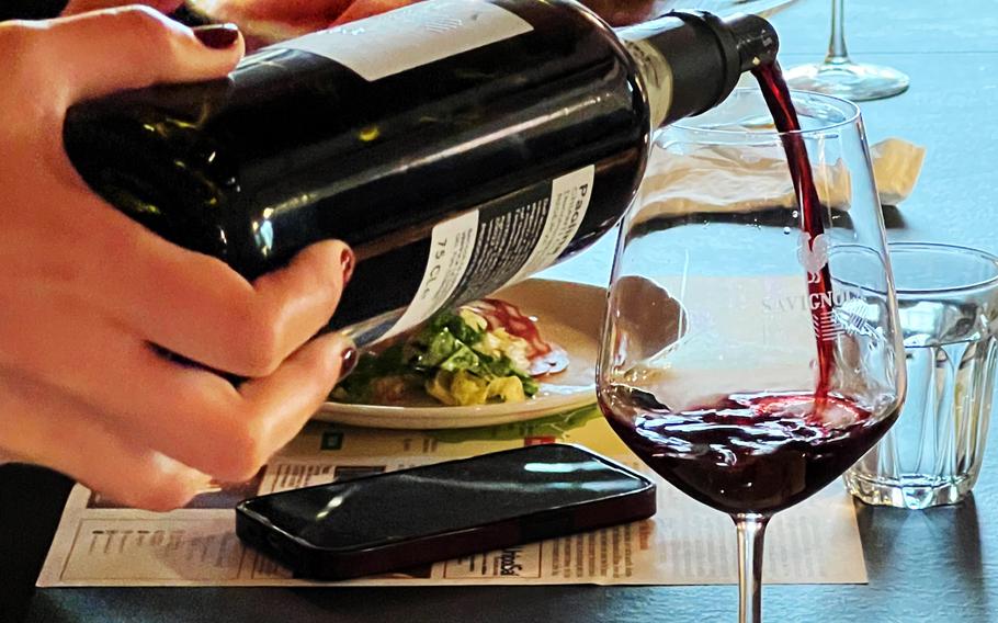 A hand pours red wine into a wine glass.