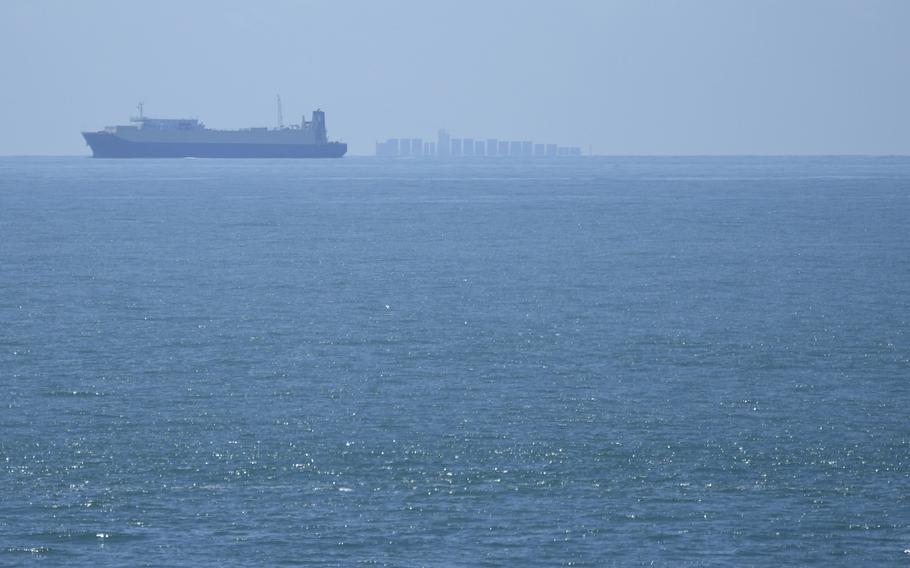 A ship is seen at sea through a haze and at a distance.