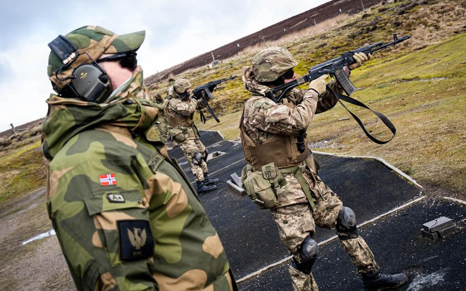 A Ukrainian soldier fires a rifle under the supervision of a Norwegian army instructor in the United Kingdom. The U.K. has been running a 35-day training course for Ukrainian volunteer fighters, which teaches them skills to survive in a hostile environment.