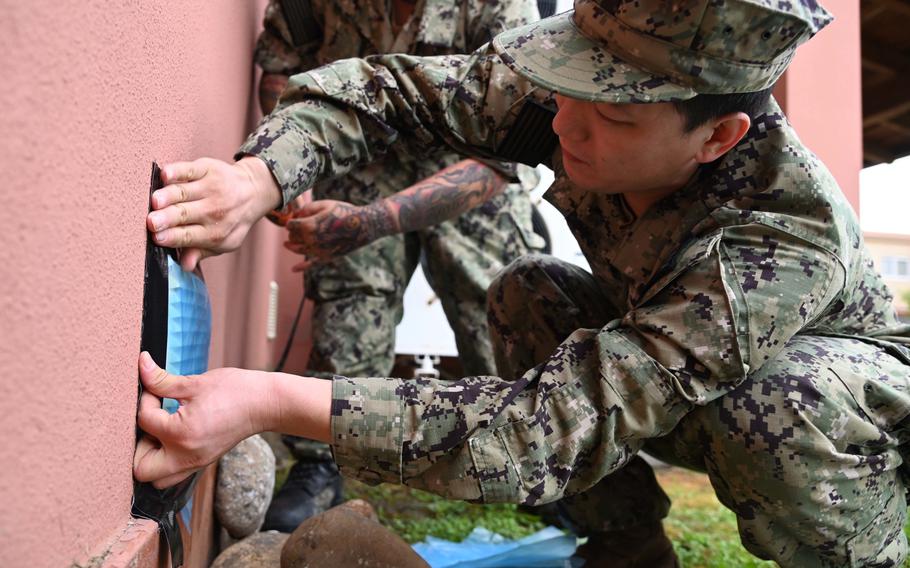 Petty Officer 2nd Class Zhijun Miao covers outside vents to prevent flooding of base housing units in preparation of a storm at Naval Air Station Sigonella, Italy, Oct. 28, 2021. Recent storms have flooded streets on base and impacted the power and drinking water supply in Sicily.