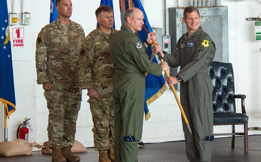 Lt. Gen. Stephen Jost, flanked by two other service members, receives the 18th Wing guidon from Brig. Gen. Nicholas Evans.