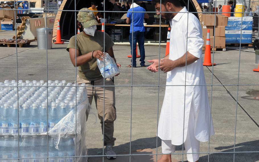 A man reaches for bottles of water inside temporary living facilities set up for Afghan evacuees at Ramstein Air Base, Germany, Aug. 21, 2021.