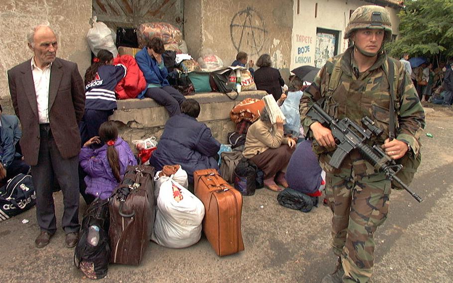 U.S. Army Sgt. Russ Carr walks among a group of Serbians in June 1999, in downtown Ferizaj, Kosovo. The Serbs, fearing retribution from Kosovo Liberation Army soldiers, were waiting for a bus to pick them up and take them away from the town. This week marks 25 years since NATO launched an air campaign that pushed the Yugoslav army out of Kosovo and prompted the Western alliance to establish a peacekeeping force in the region. 