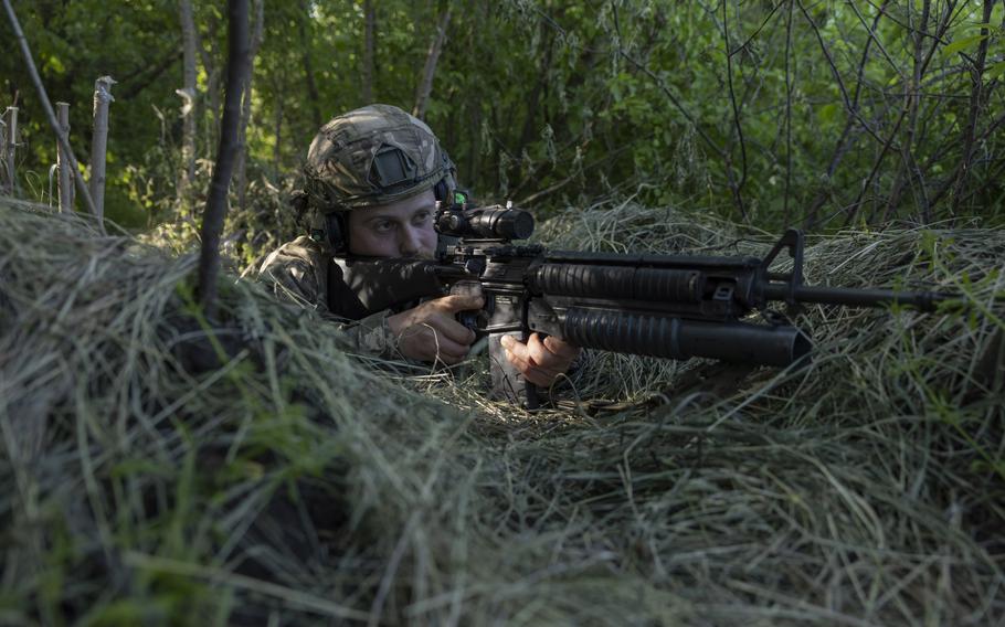 A 32-year-old private whose call sign is Luke aims an M16 with a grenade launcher. 