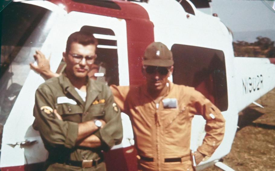 Sgt. Ron Dolecki, left, and pilot Jack Kalmbach pose with their UH-1B Huey helicopter painted in the red and white colors of the U.S. Army Corps of Engineers.