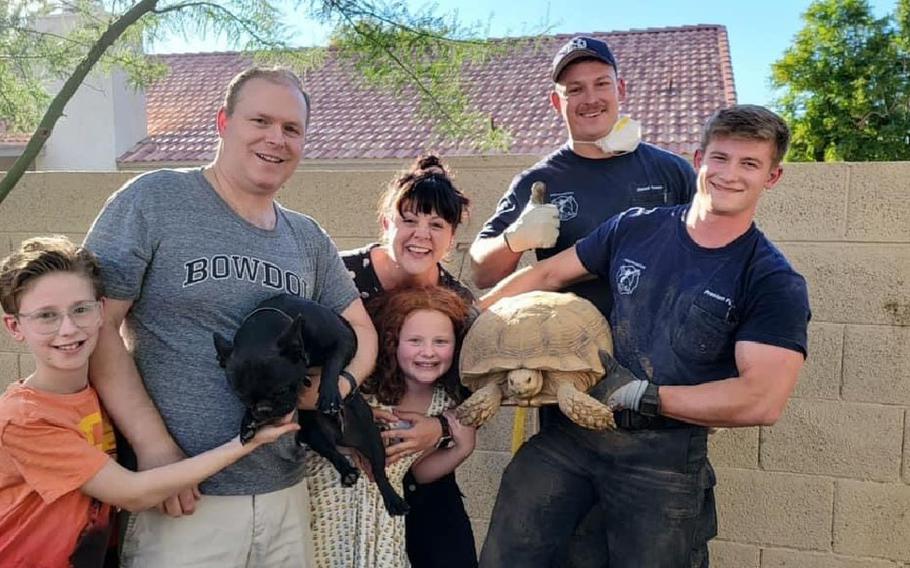 The Fortin family poses with Scottsdale, Ariz., firefighters Derek Owen and Preston Fuller after they rescued the Fortins’ pet dog, who ventured into their pet tortoise’s burrow. 