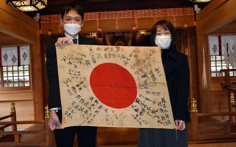 Yoshinori Goto and his wife, Miho, accept the flag of his grandfather, Japanese Imperial Army soldier Kesaji Goto, at Gokoku Shrine in Oita prefecture, Japan, Jan. 16, 2022. 