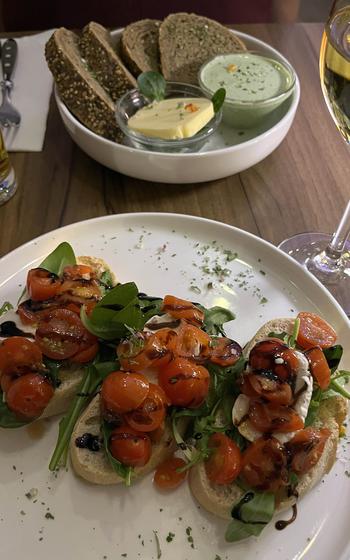 Bruschetta with marinated cherry tomatoes and goat cheese, foreground, and the house bread served with butter and Frankfurter gruene sosse, are two of the starters at Mathilda in Wiesbaden, Germany.