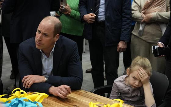 Young girl holds her head as Britain's Prince William visits an accommodation centre, for Ukrainians who fled the war, in Warsaw, Poland, Wednesday, March 22, 2023. (AP Photo/Czarek Sokolowski)