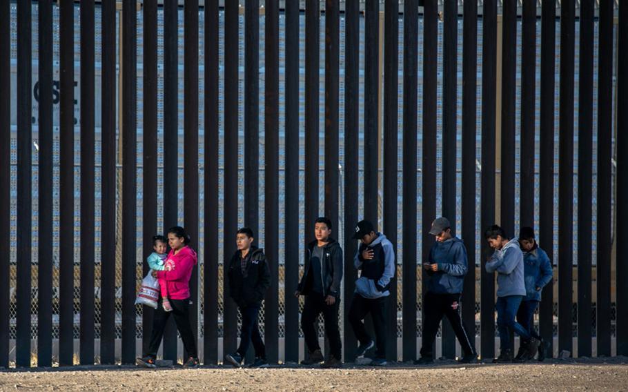 Undocumented immigrants walk along the U.S.-Mexico border wall after they ran across the shallow Rio Grande into El Paso on March 17, 2021, in Ciudad Juarez, Mexico. 