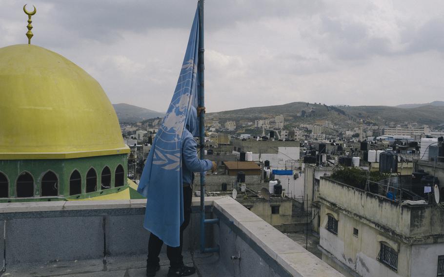 An employee raises the United Nations flag on the roof of the U.N. refugee agency’s health center in the Balata camp in the West Bank in March. The camp, the largest in the West Bank, is home to 33,000 Palestinian refugees, for whom the agency provides services including health care, education and sanitation.