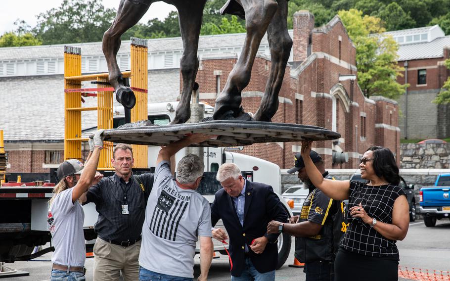 Doctor Aundrea Matthews (right) with the crew as they tape a pink pocket knife given to her by Kris Clark to honor her grandfather, who always carried it on him. They also taped a letter she wrote and a Buffalo Solider challenge coin underneath the statue. 