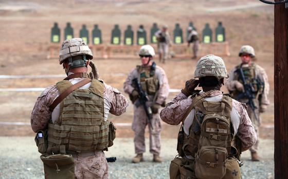 Marines with 1st Air Naval Gunfire Liaison Company adjust their ear protection before firing, aboard Marine Corps Base Camp Pendleton, Calif., Sept. 4, 2014. The 1st ANGLICO Marines conducted unknown distance shoots throughout the day as well as a pistol combat marksmanship shoot.