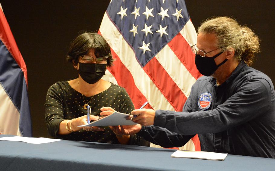 Ben Castellana, a coordinator with the Environmental Protection Agency, and Kathleen Ho, deputy director of the Hawaii Health Department, sign a joint plan at Joint Base Pearl Harbor-Hickam, Hawaii, Dec. 17, 2021, that details how the Navy’s water distribution system will be purged of petroleum contamination.