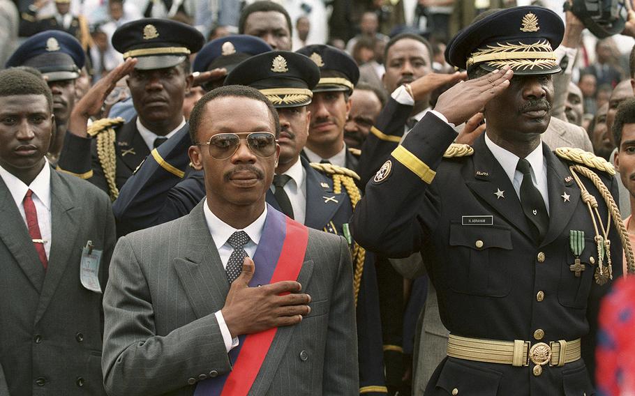 Haitian President-elect Jean-Bertrand Aristide, left, and Haitian armed forces Commander General Herard Abraham, stand at attentin during the national anthem on Feb. 7, 1991, during a ceremony at the presidential palace in Port-au-Prince. 