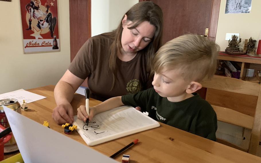 Andrea Gill, who home-schools her two children, works on a language arts problem with her son, Ren, at the family's apartment at Naval Support Activity Naples Support Site in Griciagnano di Aversa on Thursday, Dec. 9, 2021. Gill is unemployed while her husband serves his Navy tour in Italy. She is unable to work in her chosen career field teaching English as a second language due to laws that generally restrict U.S. military dependents to on-base employment. 