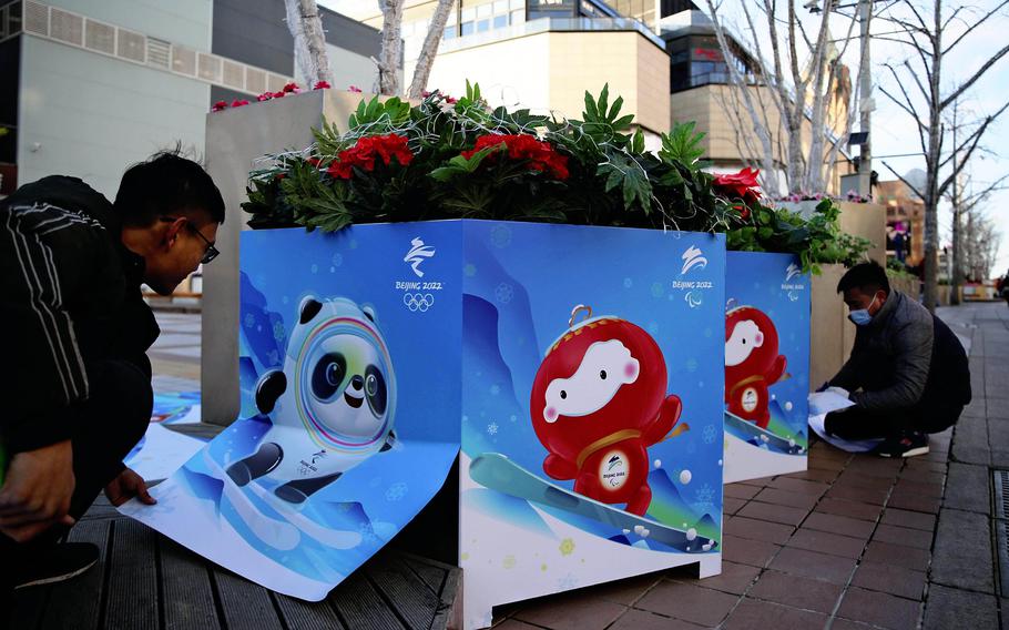 Workers put up posters featuring Beijing Winter Olympic and Paralympic mascots in Beijing.