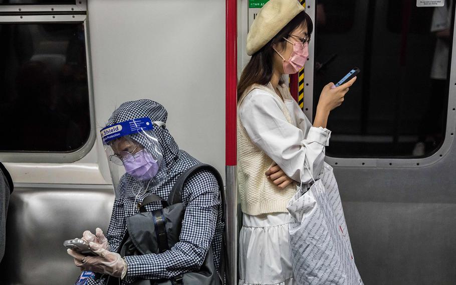 People wearing face masks as a preventive measure against the COVID-19 coronavirus commute on a train in Hong Kong on March 2, 2022.