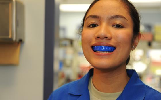 A woman smiles while wearing a mouthguard. 