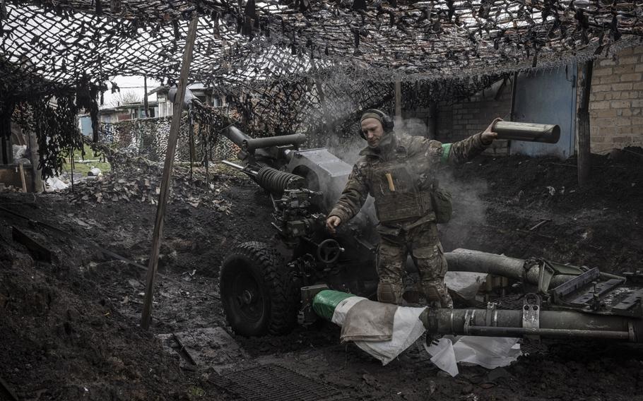 A soldier with the call sign ‘Samurai’ from Ukraine’s 77th Brigade unloads a shell casing after firing a howitzer gun on the outskirts of Chasiv Yar on April 21, 2023. 