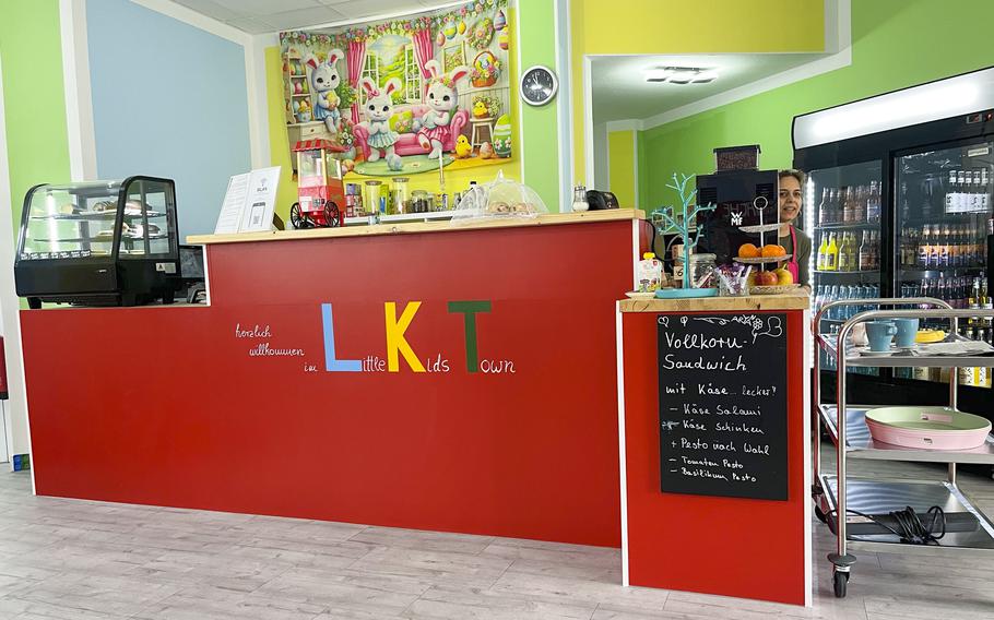 A cafe counter displays a menu, a selection of pastries and a drink cooler.