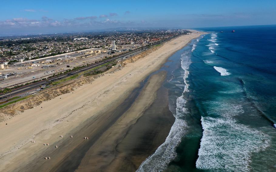 An aerial view of environmental oil spill cleanup crews picking up oil chunks off the beach Oct. 5, 2021, from a major oil spill at Huntington Dog Beach in Huntington Beach, Calif.