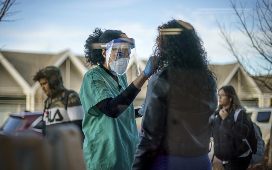 Maya Goode, a COVID-19 technician, performs a test on Jessica Sanchez outside Asthenis Pharmacy in Providence, R.I., Dec. 7, 2021. Scientists are seeing signals that COVID-19′s alarming omicron wave may have peaked in Britain and is about to do the same in the U.S., at which point cases may start dropping off dramatically. 