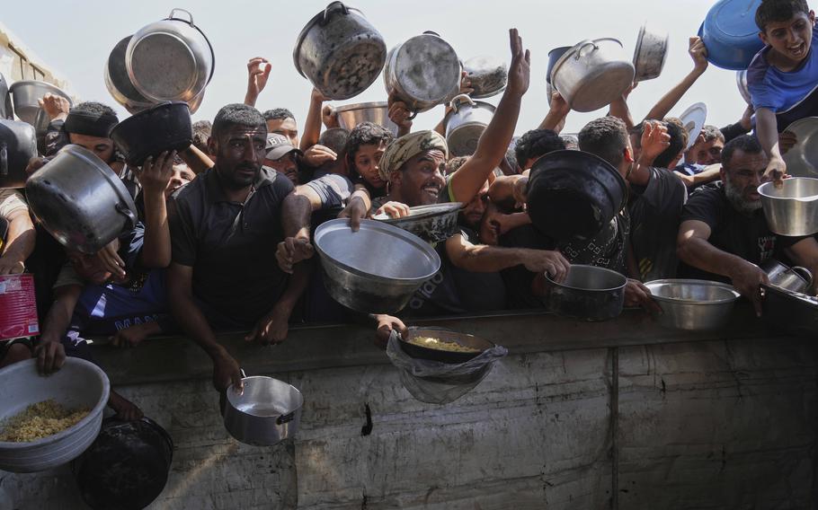 Palestinians living in Gaza ask for food at a community kitchen.
