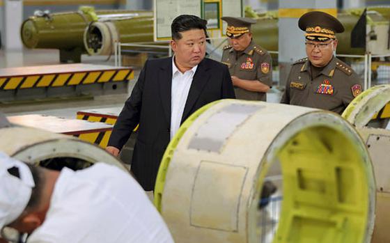 North Korean leader Kim Jong Un walks with military members while inspecting a weapons factory.