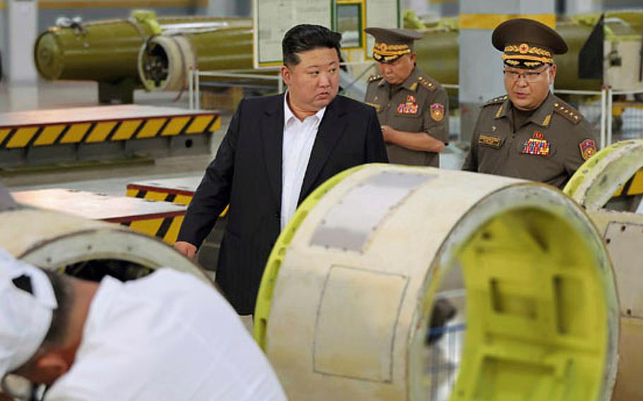 North Korean leader Kim Jong Un walks with military members while inspecting a weapons factory.