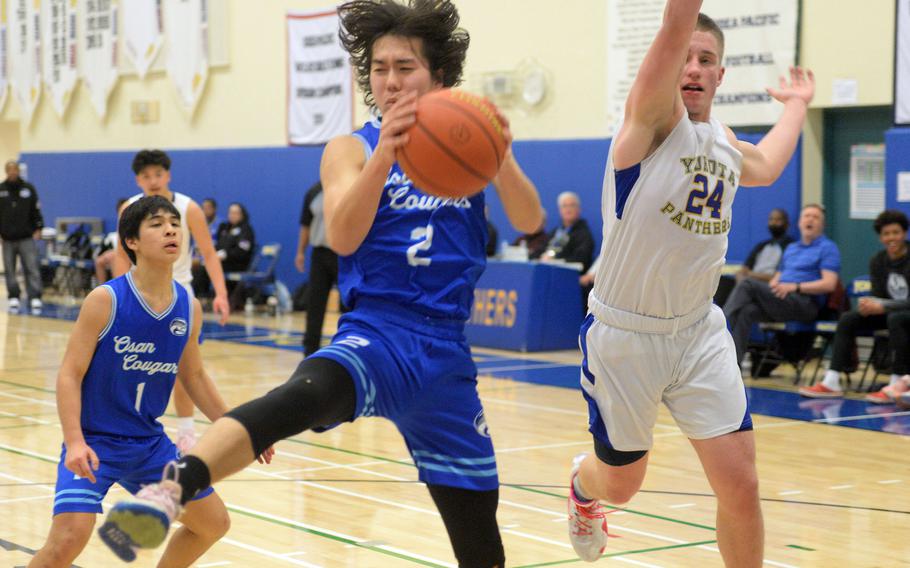 Osan’s Adam Rutland snags a rebound in front of Yokota’s Matthew Hullman during Wednesday’s boys D-II final.