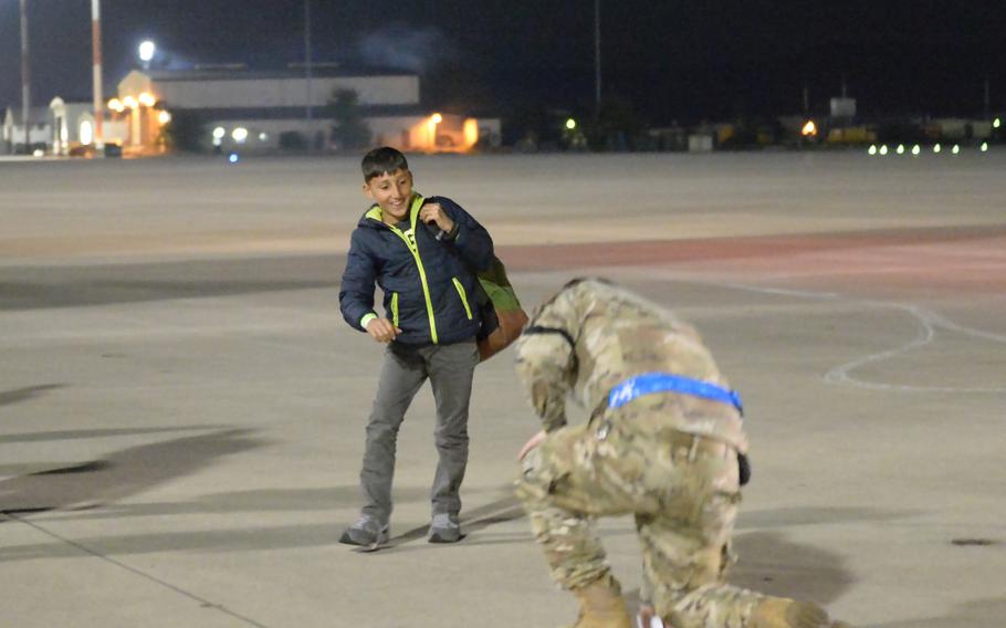 An Afghan boy breaks away from the group of evacuees he is traveling with on Saturday, Oct. 9, 2021, to fist-bump an airman at Ramstein Air Base, Germany. 