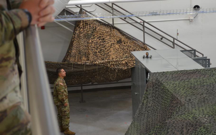 A soldier is standing and looking up a small drone that is preparing to launch.