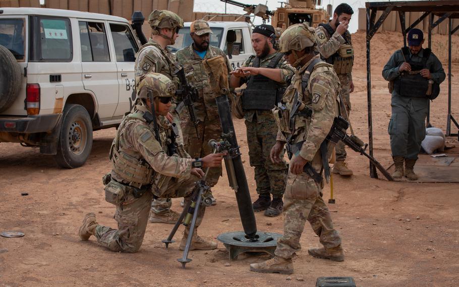 Soldiers in camouflage combat gear gather around a mortar position.
